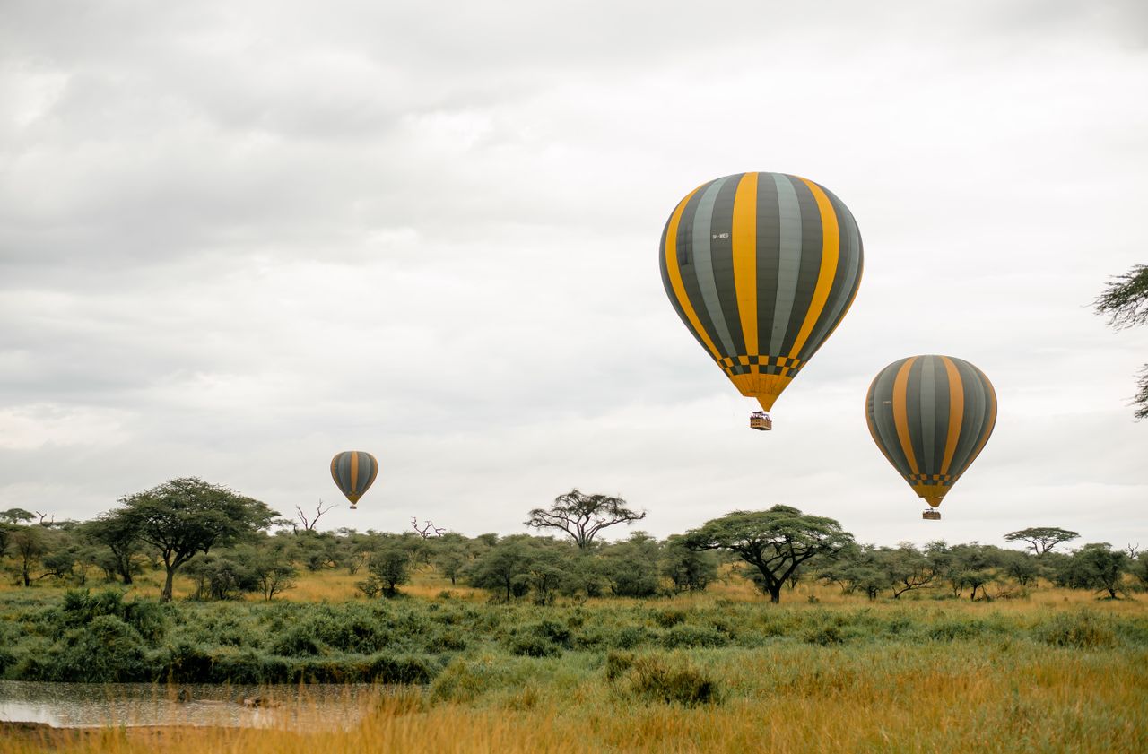 Captivating hot air balloon ride over the serene African savanna under a cloudy sky.