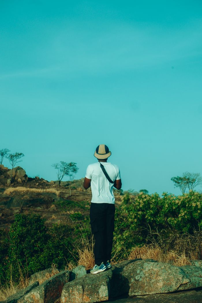 A person stands on a rock overlooking the natural landscape of Jos, Nigeria.